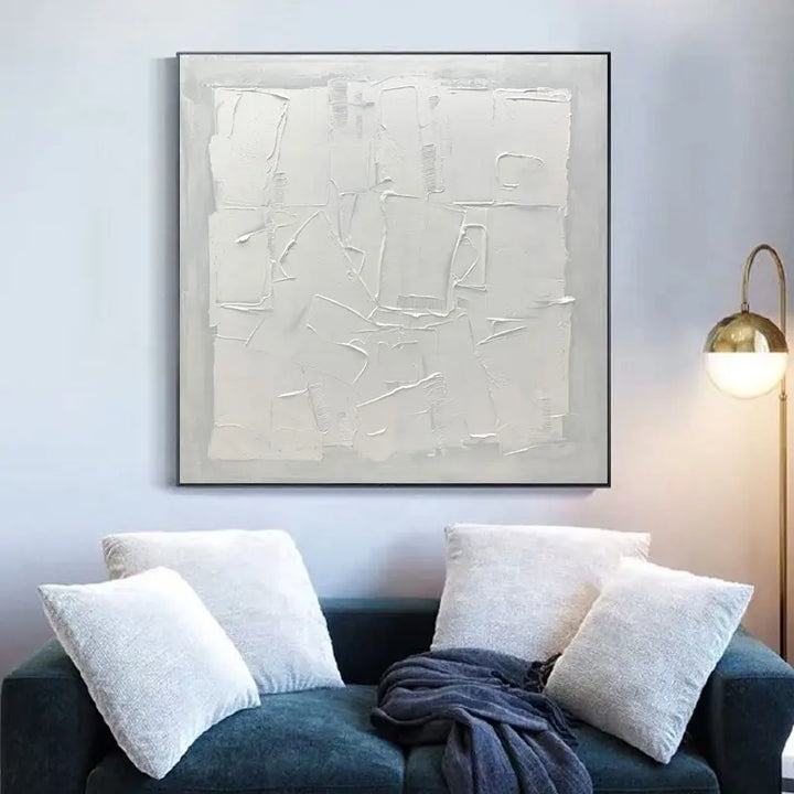 A white abstract painting hangs above a couch, adding a touch of elegance to the room's decor.