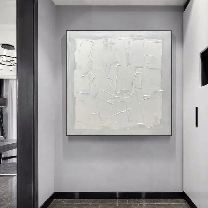 A white painting hangs in a hallway, adding elegance and brightness to the space.