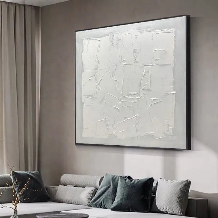 A white abstract painting hangs above a couch, adding a touch of elegance to the room's decor.