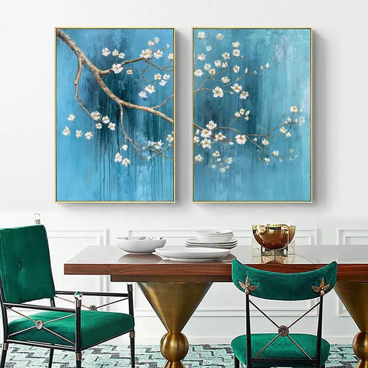 Two floral paintings hang above a dining table, adding color and beauty to the room's decor.